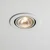 A standard halogen GU10 Par16 spotlight with a clear glass lens and a textured reflector is installed in a white ceiling. The bulb emits a warm white light, creating a focused beam.